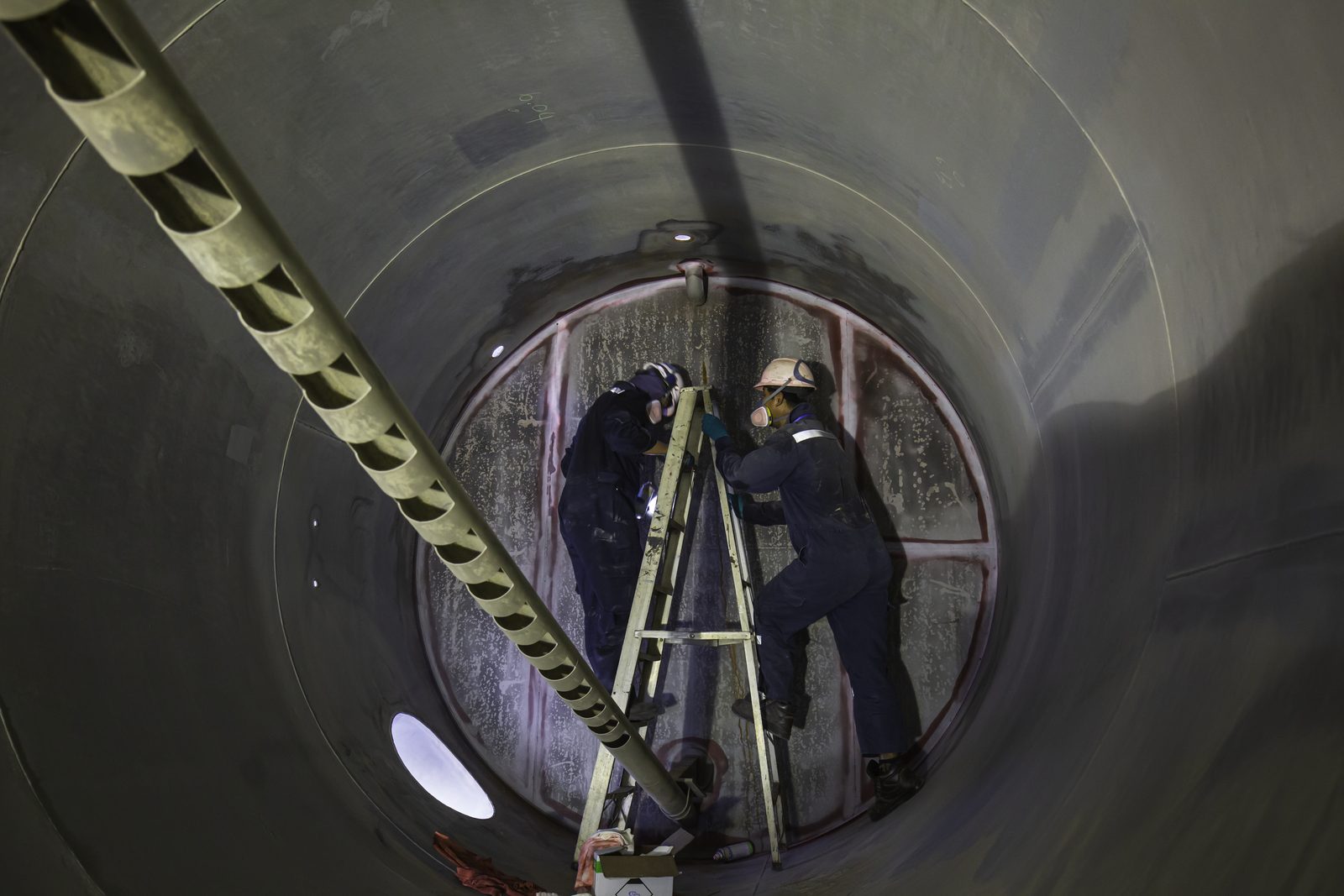 Personal descendiendo al interior de un tanque industrial durante una maniobra
