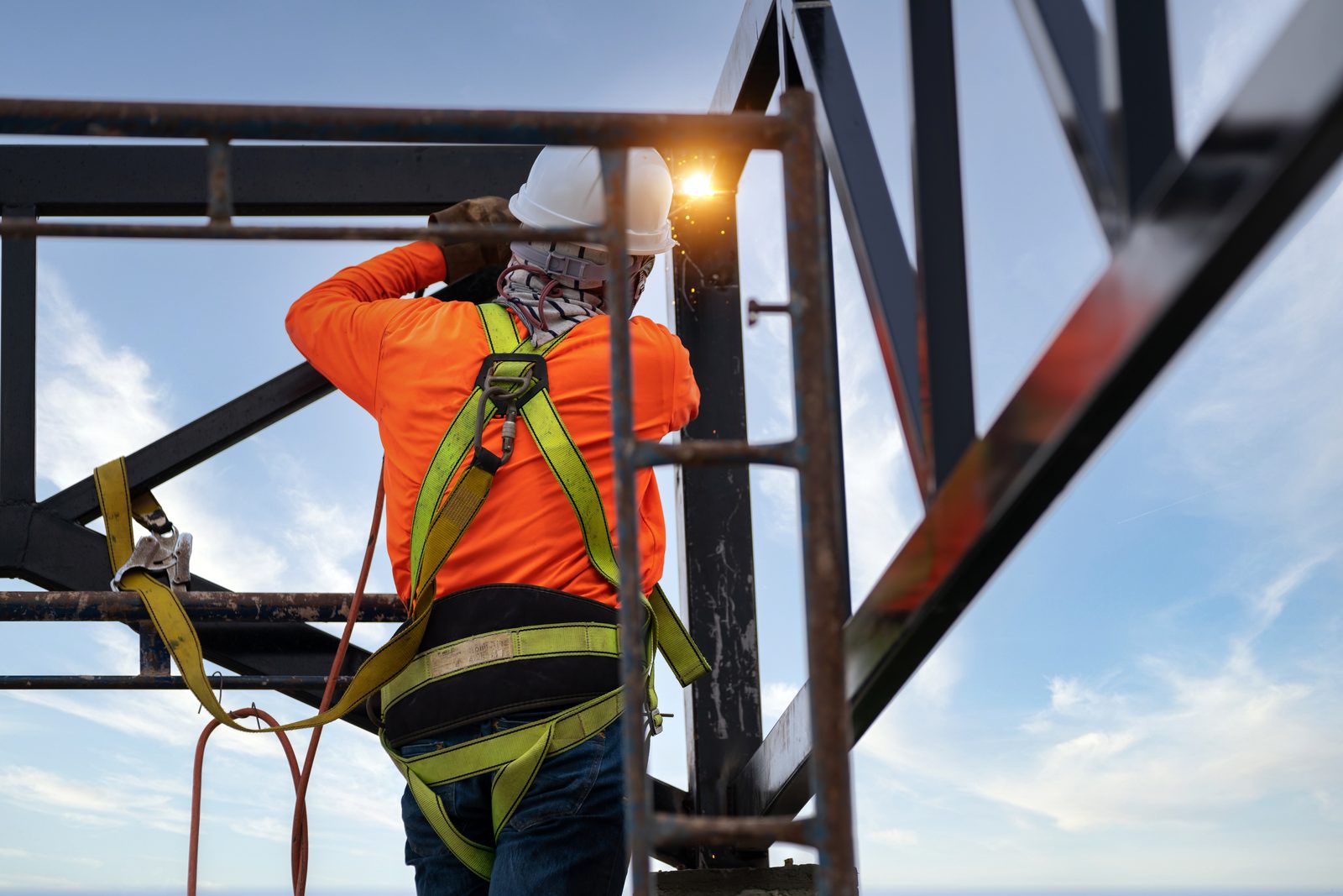 Trabajador con arnés de cuerpo completo sobre una estructura metálica